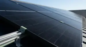 Vista angulada y detallada de filas de paneles solares monocristalinos negros de alta eficiencia, con textura de célula visible, instalados profesionalmente en el tejado de una vivienda bajo un cielo azul despejado. Enfatiza la precisión y el rendimiento. Sin texto ni logos.